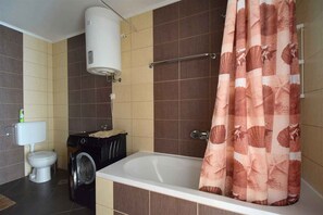 Ein Badezimmer mit Badewanne, Toilette, Waschmaschine und Handtuchhalter.