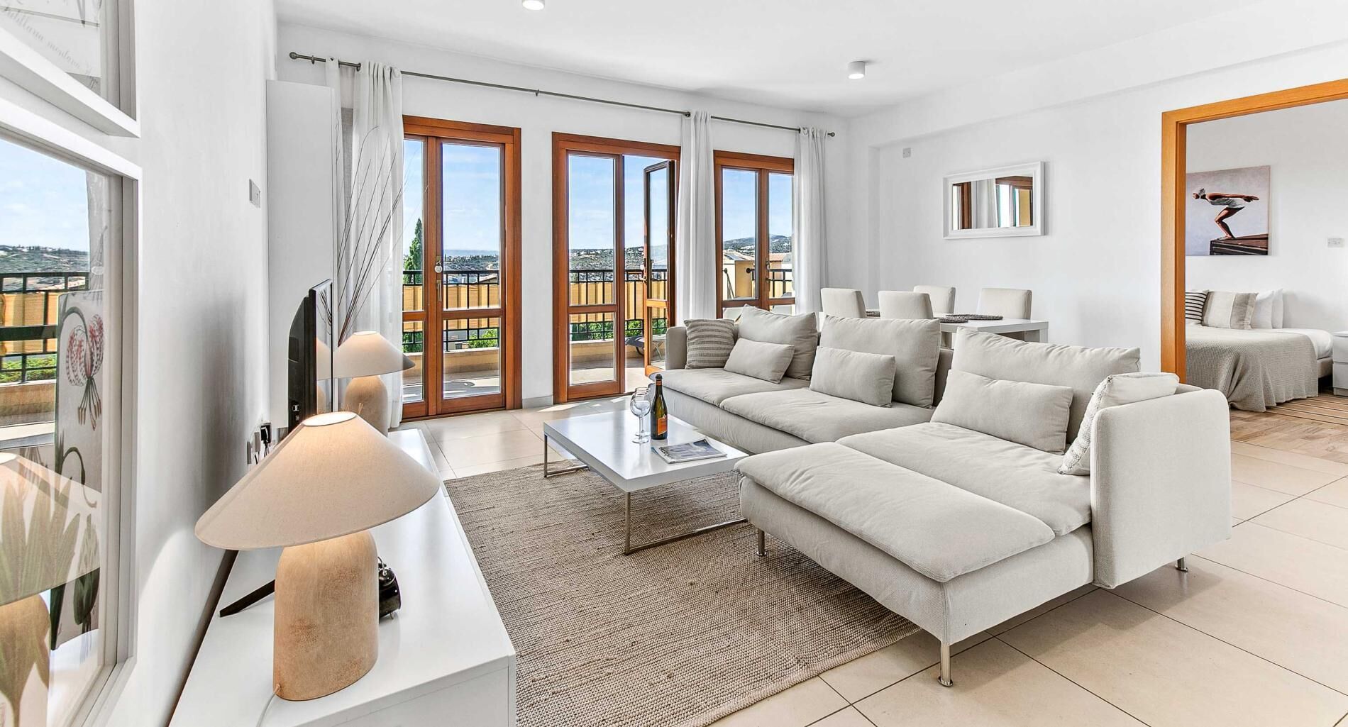 A modern living room with a sofa, coffee table, and a view of the city through large windows.