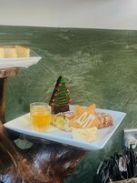 Una bandeja de postres con pastel, un pastel con forma de árbol de Navidad, un sándwich y una bebida sobre un plato blanco.