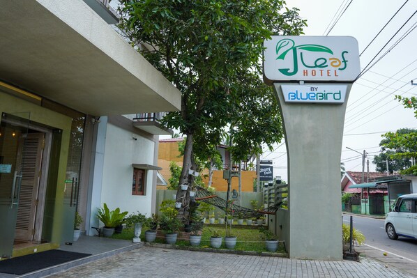 A hotel sign with a hammock and potted plants in front.