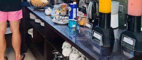Montaje de bufé con diversos alimentos, bebidas y utensilios.
