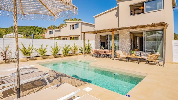 Ein modernes Haus mit Swimmingpool, Gartenmöbeln und einer Pergola.