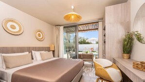 Ein modernes Hotelzimmer mit einem Bett, einem Schreibtisch, einem Sessel und einer Hängeleuchte, mit Blick ins Freie.