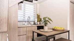 Eine moderne Küche mit Holzausstattung, eingebautem Spülbecken, einem Blumentopf und einem Obstkorb auf einem Tisch.