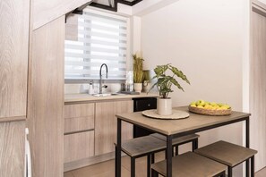 A modern kitchen with wooden cabinets, a built-in sink, a potted plant, and a fruit basket on a table.