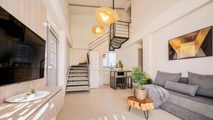 Ein modernes Interieur mit Treppe, Küchenbereich, einer Couch und einem Esstisch.