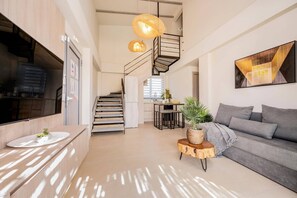 A modern interior with a staircase, a kitchen area, a sofa, and a dining table.