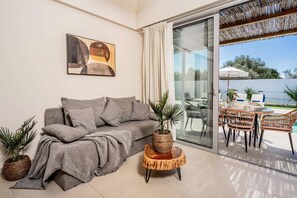 Una sala moderna con un sofá gris, una mesita tejida y una planta en maceta.