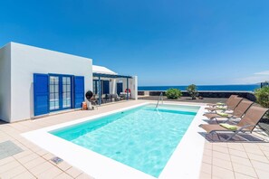 A pool area with two pools, blue doors, and lounge chairs. - Villa Seasol 2 by Villa Plus (Playa Blanca)