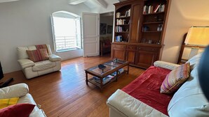 Un salon avec un canapé blanc, un canapé rouge, une table basse en bois et une bibliothèque.