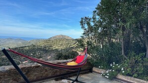 Un hamac sur une terrasse en pierre, donnant sur un paysage montagneux sous un ciel dégagé.