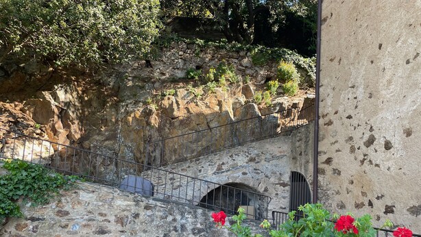 Un escalier en pierre avec des rampes métalliques, menant à une avancée rocheuse.