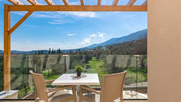 A balcony with a table and chairs, offering a view of a mountainous landscape.