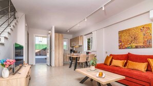 A modern living room with a red sofa, a wooden coffee table, and a kitchen in the background.