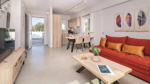 En moderne stue med køkken, spiseområde og en rød sofa med puder.