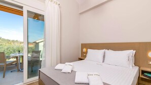 Et hotelværelse med seng, et natbord, et vindue med gardiner, udsigt til det fri og et lille bord med stol.