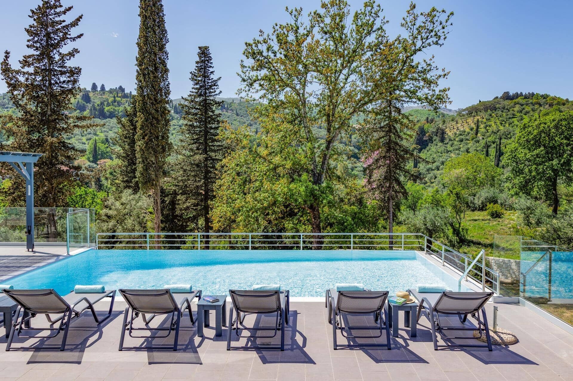 Área de piscina com espreguiçadeiras e vista para uma paisagem montanhosa.