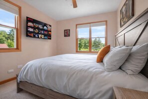 Une chambre à coucher avec un lit, un ventilateur de plafond, une fenêtre et une affiche accrochée au mur.