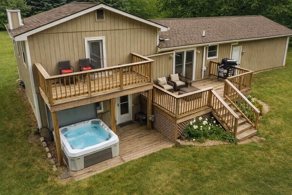 Une maison à deux étages dotée d’un jacuzzi, d’un espace salon extérieur et d’un coin barbecue.