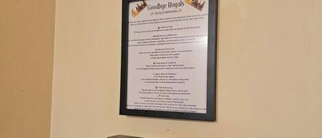 A framed sign with checkout instructions for a hotel, including sections for rooms, dining, and trash disposal.