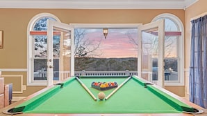 A pool table with a scenic view through large windows, a pool cue, and a set of balls. - Cozy 4BR/4BA Cabin in Ellijay • Pets • Hot Tub (Ellijay)