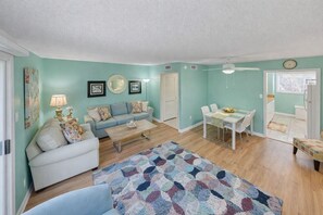 Uma sala de estar com sofá, mesa de centro e um espaço de jantar com mesa e cadeiras.