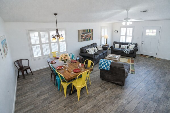 A spacious living area with a dining table set for four, a sofa, and a loveseat.