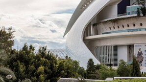 A modern building with a curved facade, large windows, and a rooftop garden.