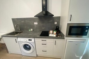A compact kitchen with a washing machine, a microwave, and a built-in oven. - Travel Habitat Cabanyal Loft 3 (Valencia / València)