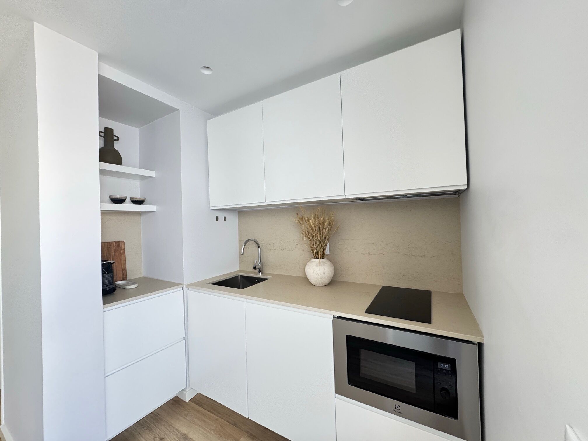 A modern kitchen with white cabinets, a stainless steel oven, and a sink.