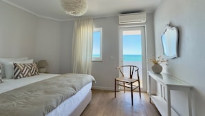 Ein Schlafzimmer mit Bett, Stuhl, Fenster mit Aussicht, Klimaanlage und Deckenleuchte.