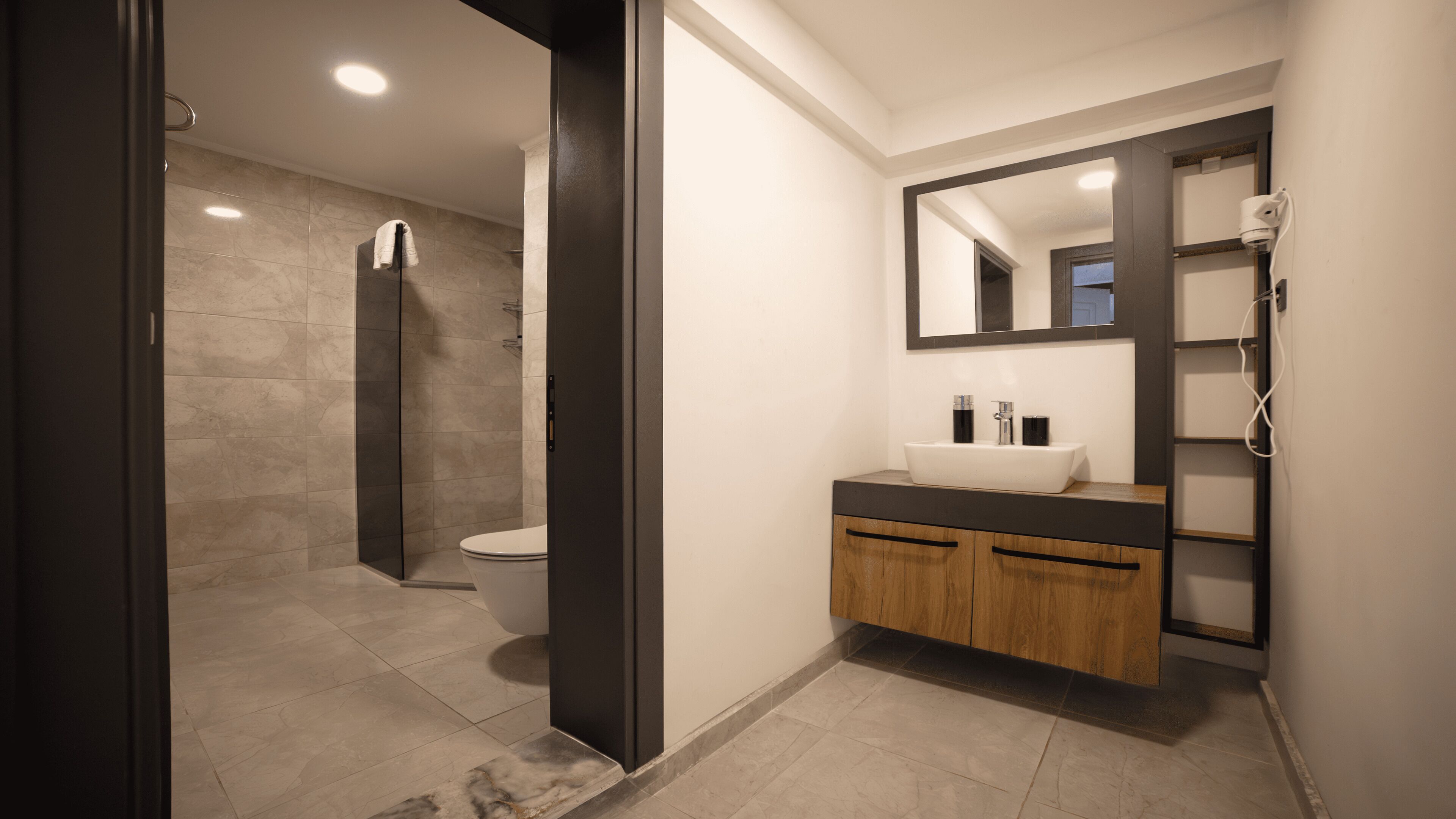 Un baño moderno con ducha a ras de suelo, inodoro y tocador con espejo.