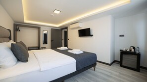 A modern hotel room with a large bed, a flat-screen TV, a desk with a kettle, and a water bottle. - Kriti Hotel Antalya (Antalya)