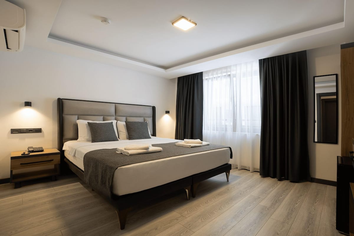 A modern hotel room with a large bed, bedside tables, a desk, and a television.