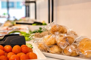 Una mesa de buffet con diferentes alimentos, incluyendo panecillos y tomates.