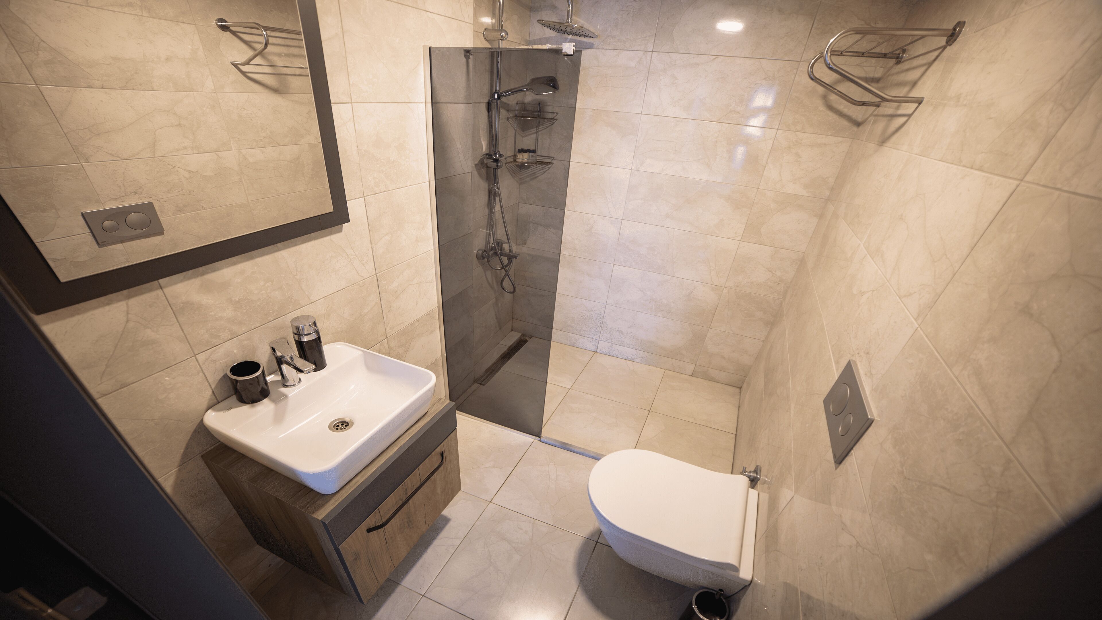 Een moderne badkamer met een douchecabine van glas, een witte wastafel en een toilet.
