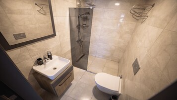 Un baño moderno con ducha de vidrio, lavamanos blanco y un inodoro.