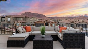 Ein Balkon mit einem Ecksofa, einem Topfpflanzen und einem Couchtisch.