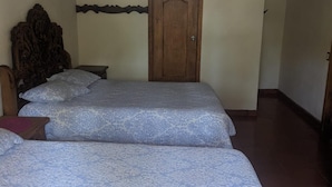 A room with three beds, a wooden door, and a light fixture above the door.