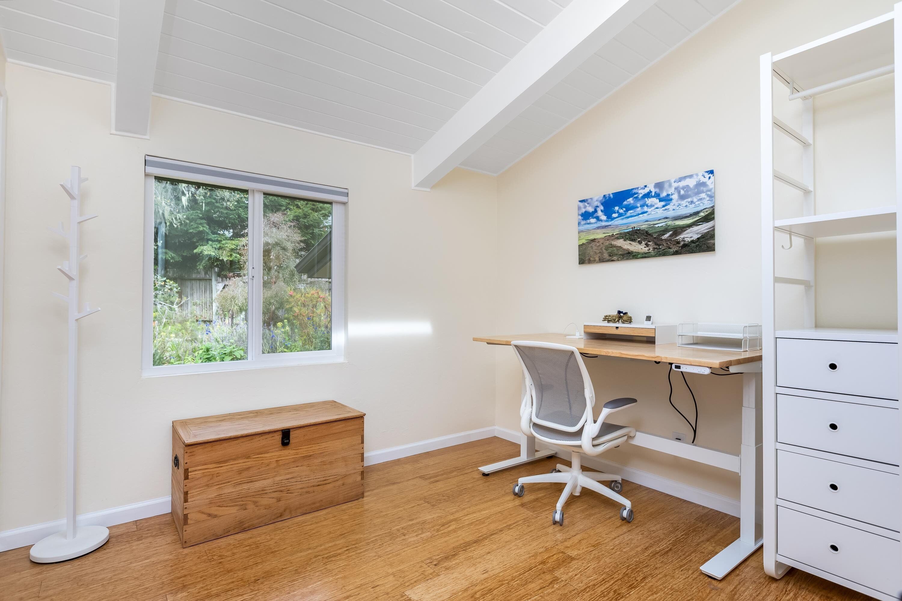 A room with a desk, chair, and a wooden chest of drawers.