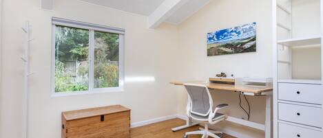 A room with a desk, chair, and a wooden chest of drawers.