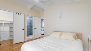 A bedroom with a large bed, a wardrobe, and a sliding glass door leading to a balcony. - Tranquil Treehouse - EV Charger (Cambria)