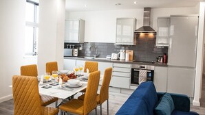 Una cocina moderna con armarios blancos, horno empotrado y campana extractora de acero inoxidable.