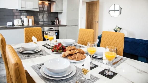 Un comedor moderno con una mesa de mármol preparada para el desayuno, con cruasanes, fresas y zumo de naranja.