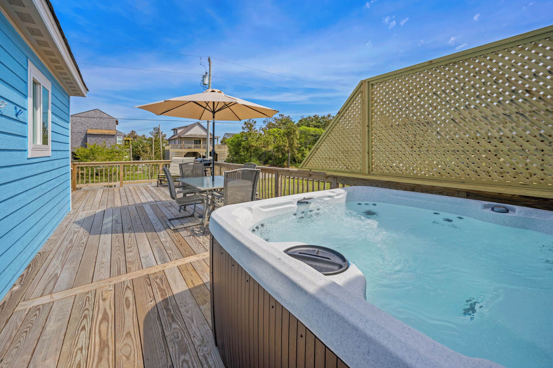 A wooden deck with a hot tub, outdoor furniture, and a pergola.