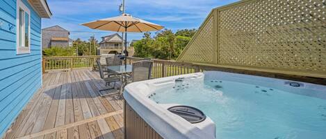 A wooden deck with a hot tub, outdoor furniture, and a pergola.