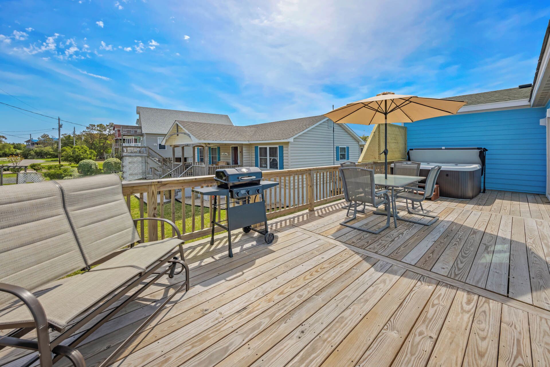 A wooden deck with outdoor furniture, a grill, and a hot tub.