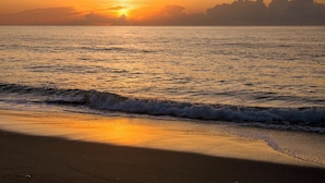 Une plage au coucher du soleil, avec des vagues qui se rapprochent du rivage.
