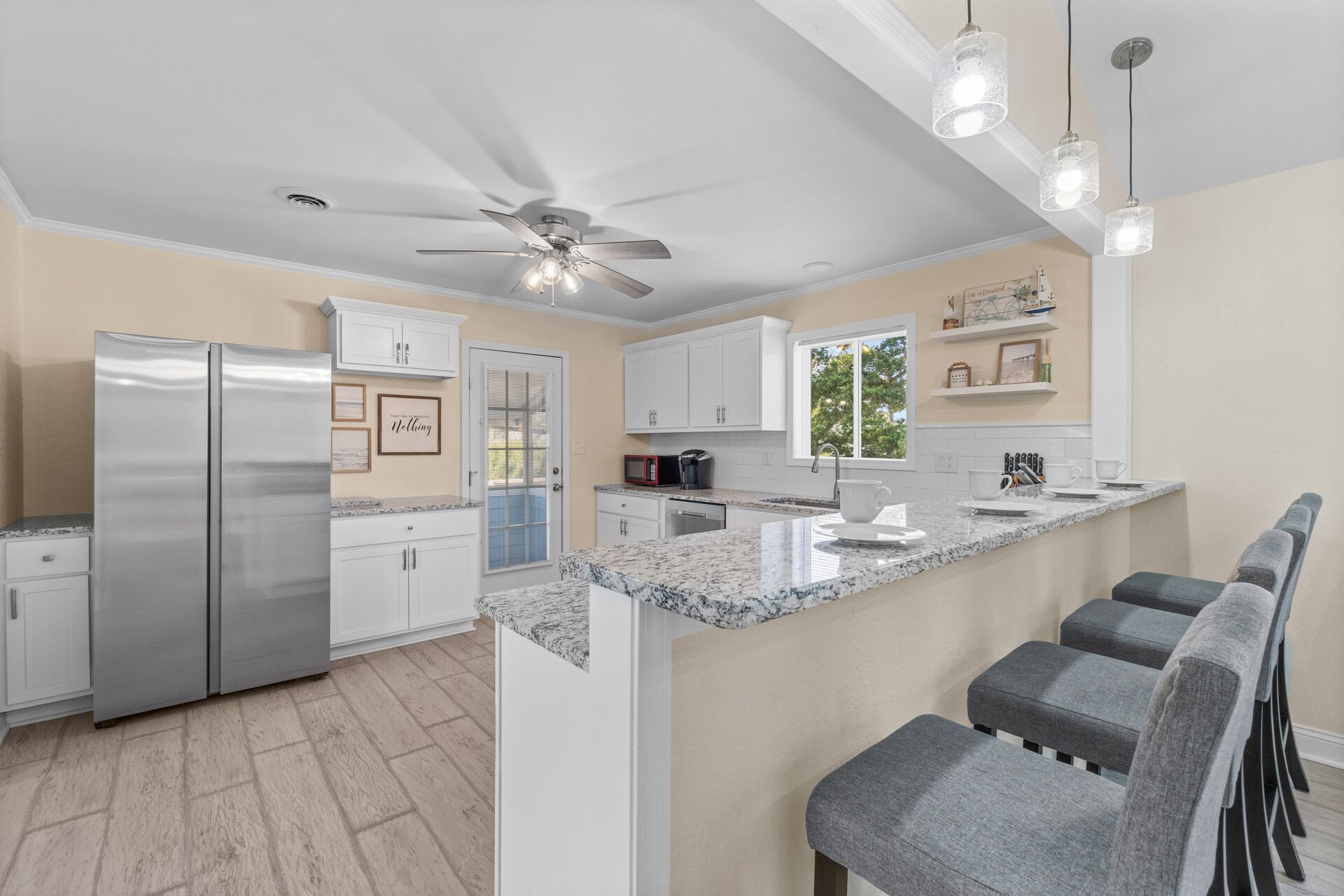 A modern kitchen with a central island, white cabinetry, and a ceiling fan.