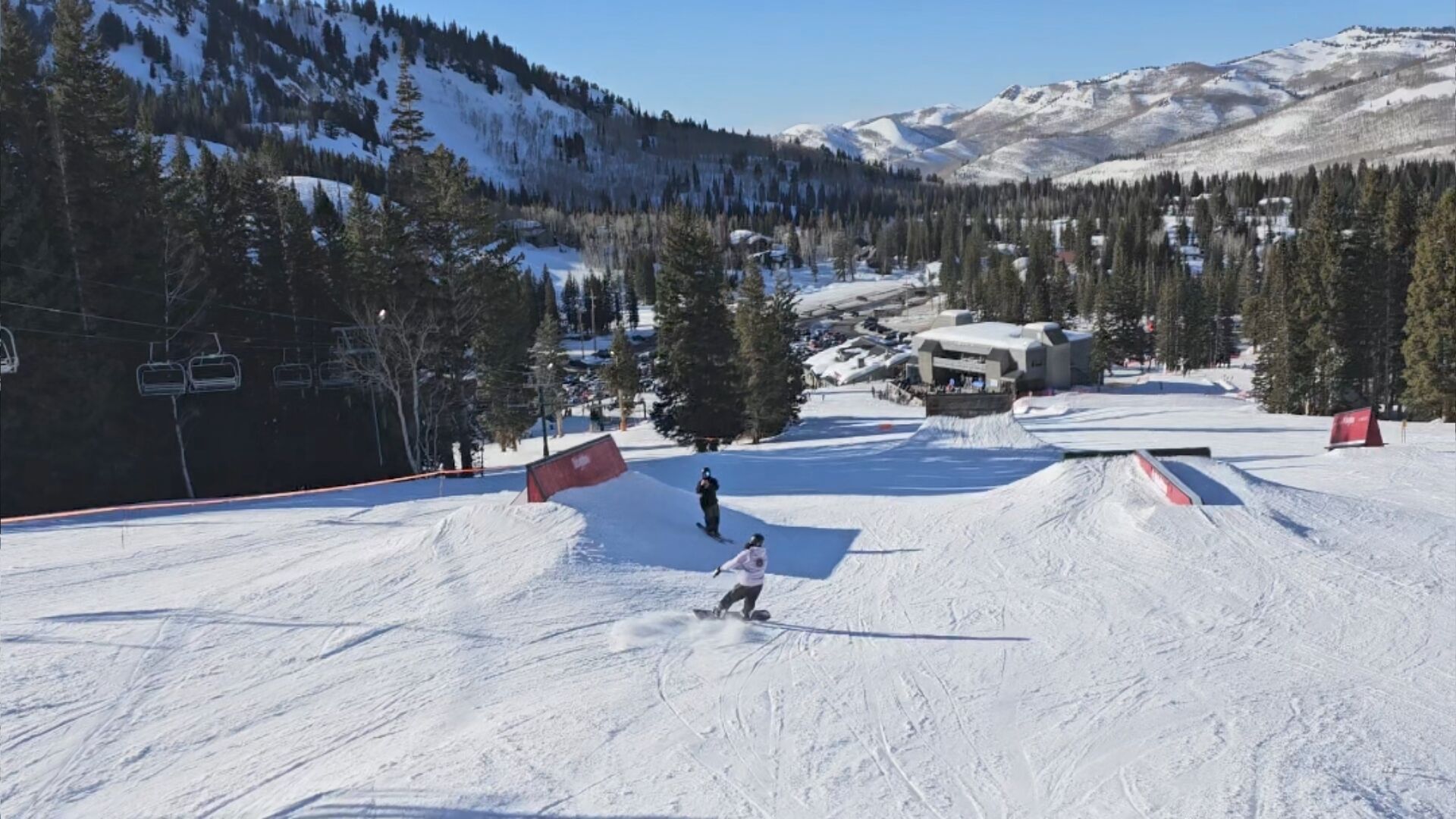 A ski slope with a chairlift, trees, and a mountain backdrop.